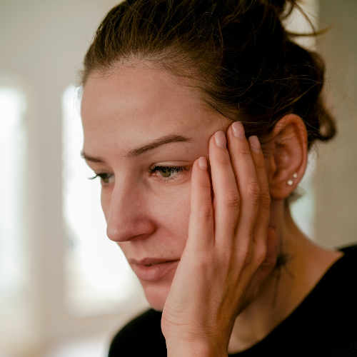 Young woman holding the side of her face with worried look